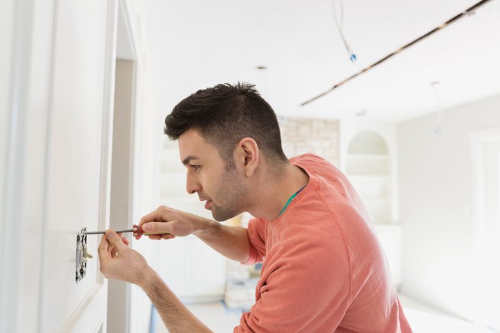 Polk Electric LLC | Young man installing light switch at home